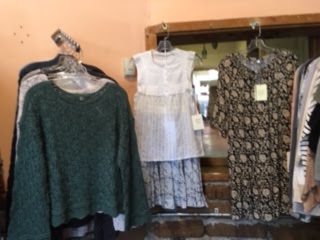 Green sweater and cream knit pieces hanging on a rack in the store