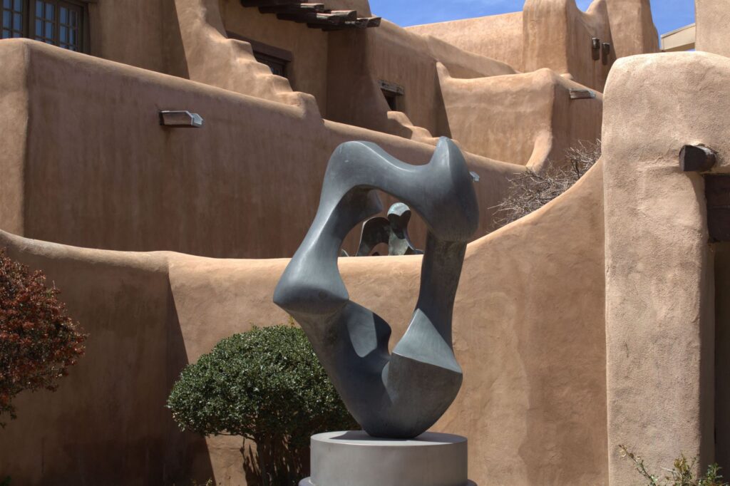 Sunlit Pueblo Revival adobe walls and a bronze sculpture in Santa Fe, New Mexico